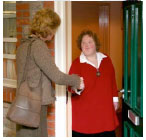 Two women shaking hands at a front door