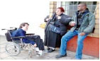 A man in a wheelchair talking to a man and woman on the street
