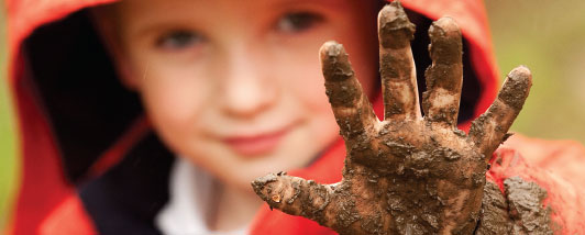 Child holding up his muddy hand