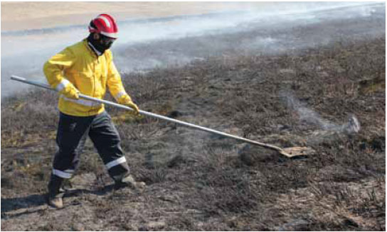 Photo B10.7 Firefighter using a long handled metal scraper