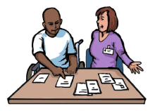 A man in a wheelchair using low tech communication equipment to make decisions. A professional woman is sitting next to him and watching him make his choice.