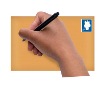 Hand holding a pen and writing on envelope, with a stamp in top right hand corner of envelope