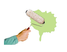 Hand holding a paint roller and painting with green paint