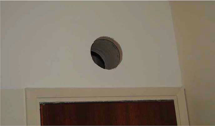 A picture of a hole in the wall showing a breach of fire-resisting enclosure