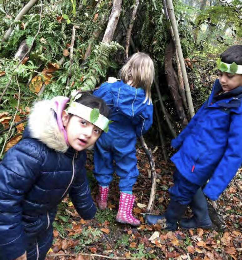 Young children using outdoor materials to play, make head bands and build dens in the woods.
