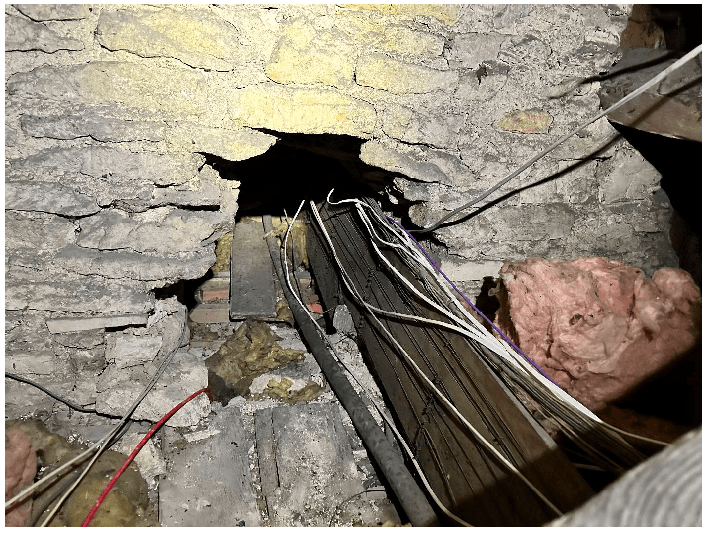 Opening in a separating wall originally for bell wires, latterly cables.