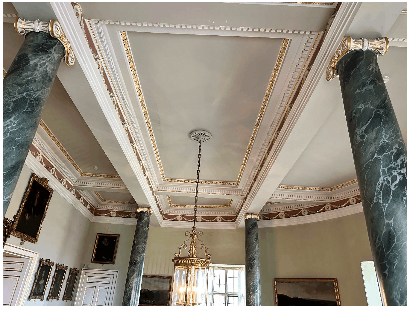 Image of an ornate ceiling with ventilation holes around a chandelier