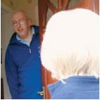 A woman talking to a man at his front door