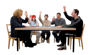 People sitting at a takle with hands in the air