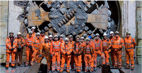 Picture showing workers standing in front of a drill used for excavating a tunnel 