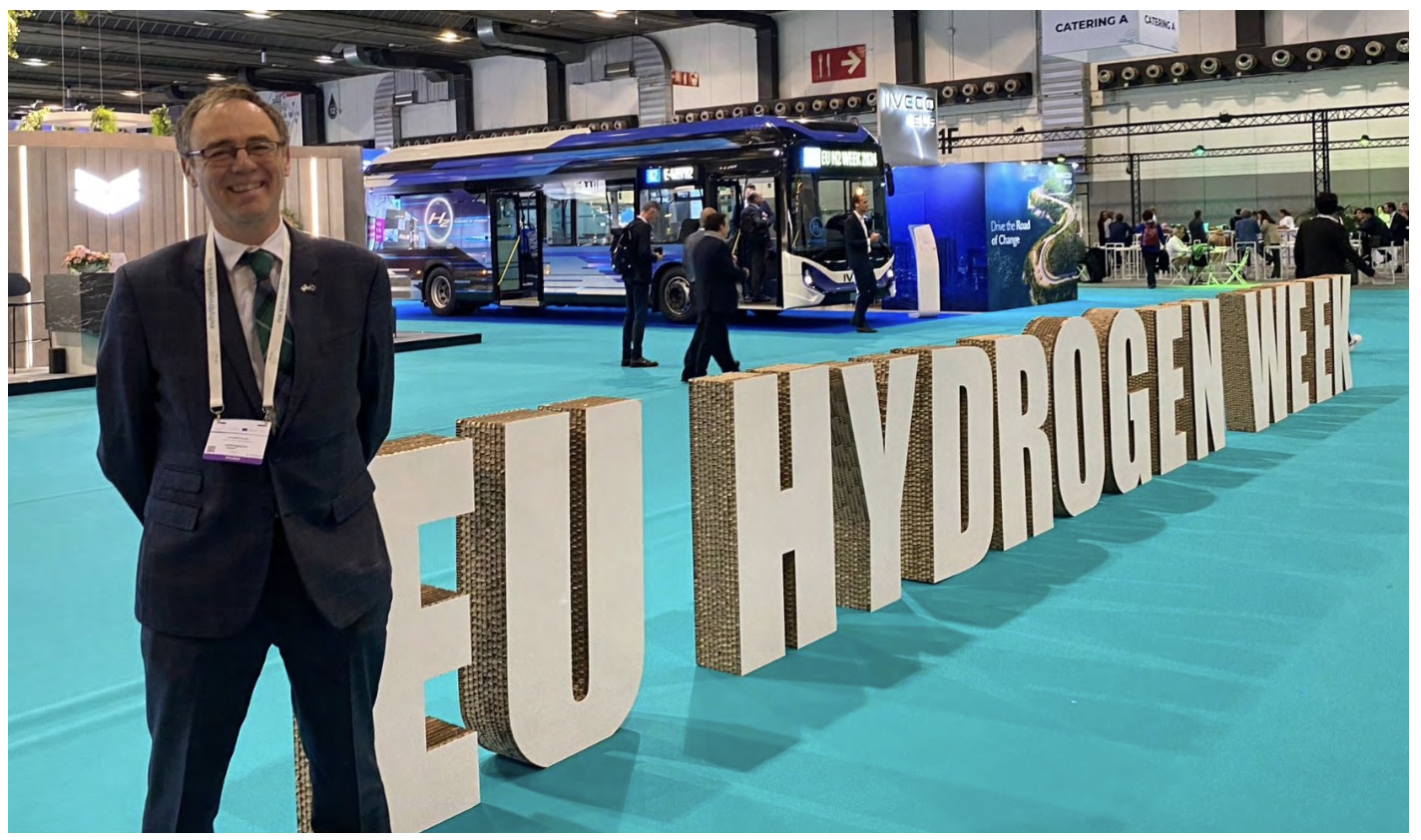The Minister for Climate Action stands beside large 'EU Hydrogen Week' sign.