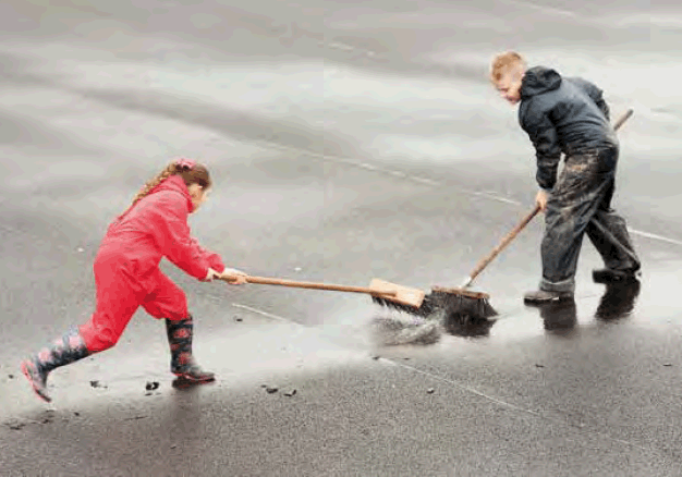 children sweeping puddles