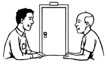Two men in a room behind a closed door, sitting at a table and talking happily