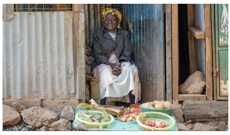 Weremasia sits on her front doorstep with produce in baskets to sell.