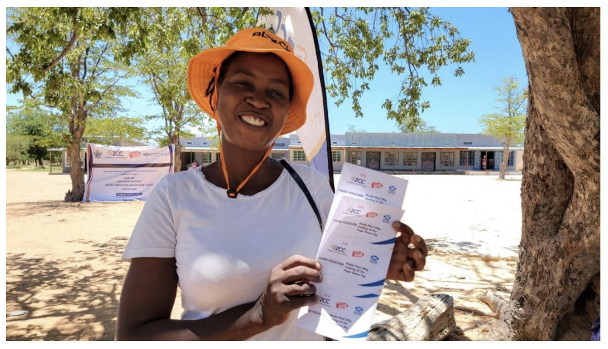Sithandazile smiles as she holds up food vouchers.