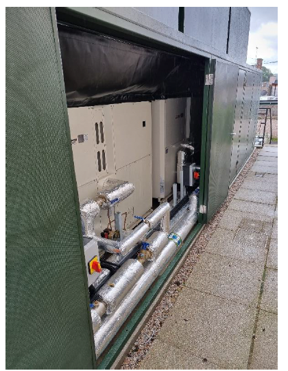 Three air source heat pumps within a green soundproof enclosure.