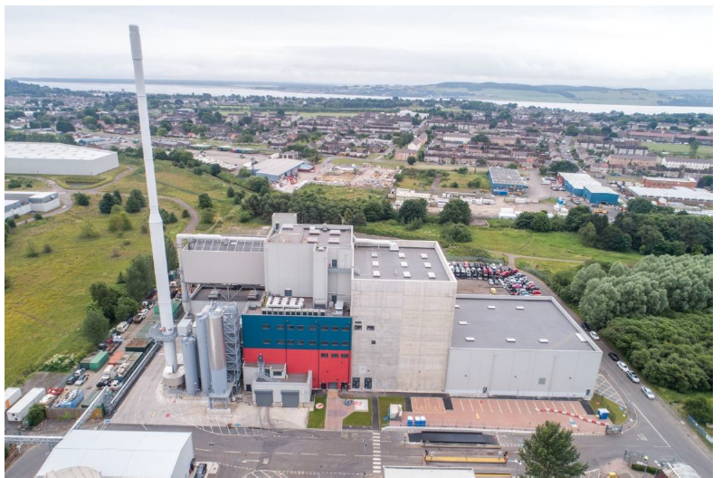 Aerial view of the Baldovie Energy from Waste facility buildings with a tall tower to the left hand side of the image. 


