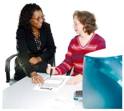 Two women sitting at a desk completing a form