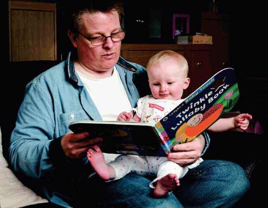 man and baby reading book