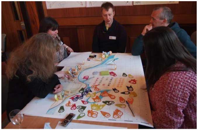 is a photograph of a group of participants using the map and icons to discuss different offshore renewable scenarios.