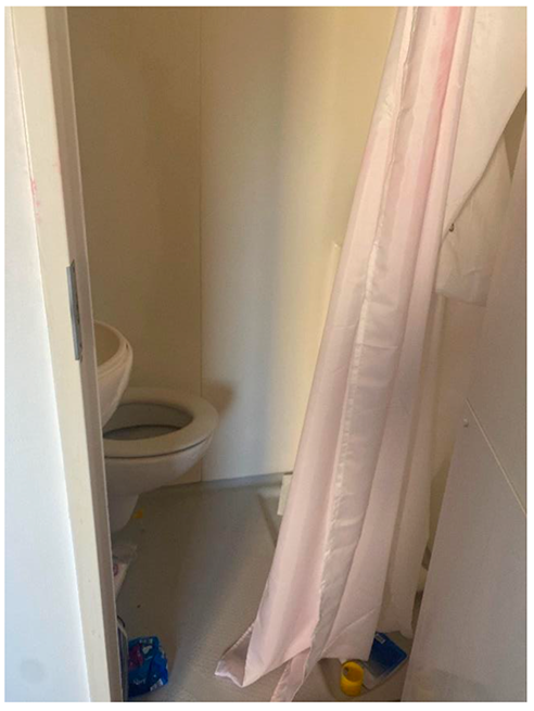 A toilet in small bathroom, with a curtain over the door.