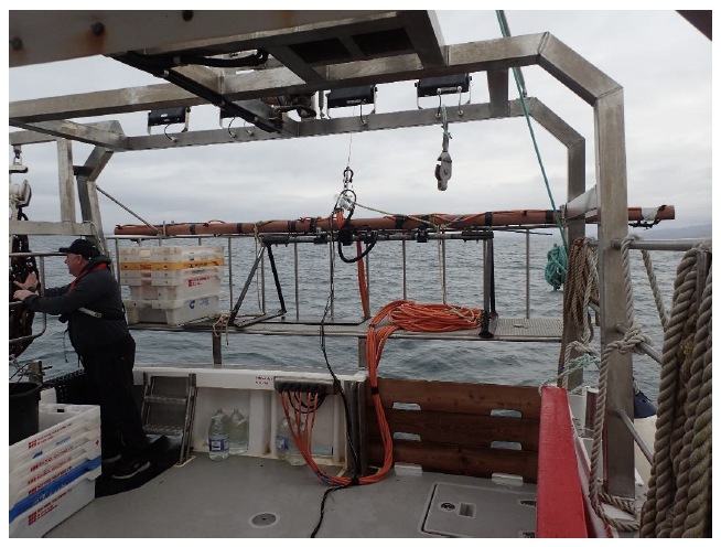 A photo of the aft deck of fishing vessel Skye showing the electrofishing and video sled equipment stowed on the aft deck platform. The electrical cables feeding the electrofishing electrodes can also be seen.