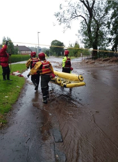A group of people carrying a raft during a flood in Tilicoultry. 