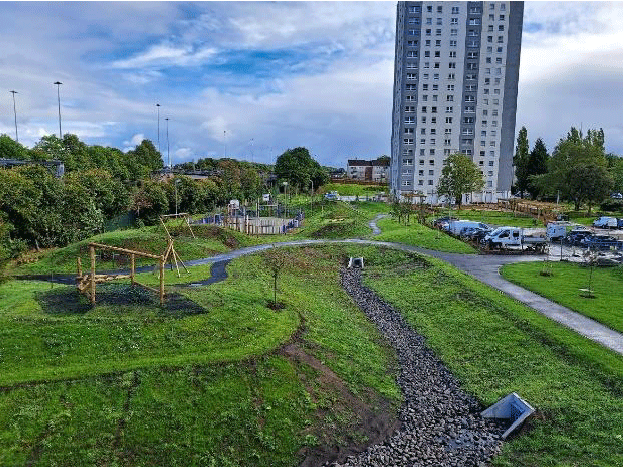 A photo of Queensland Gardens Community park with a large building in the background. 
