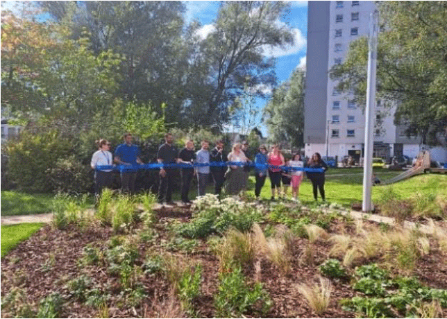 A photo of the opening of the Queensland Gardens Community Park showing group of people standing in a line in the park.