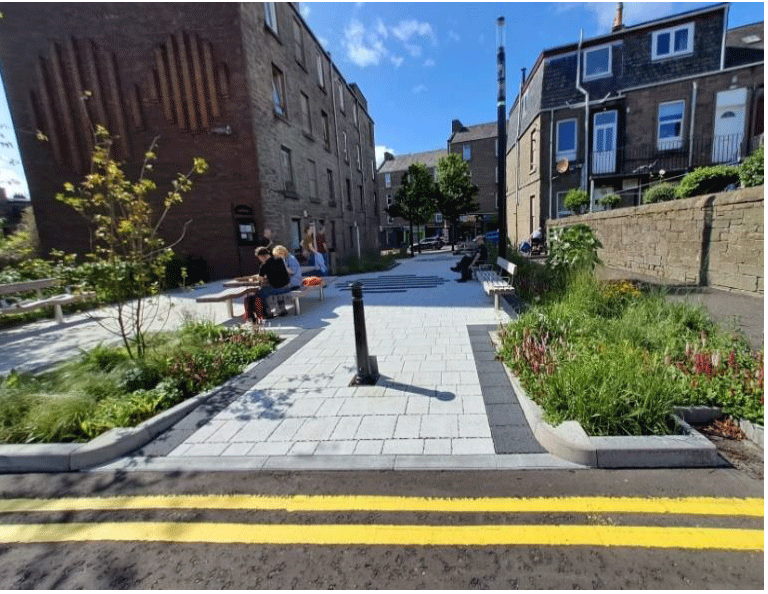 A  photo showing Criagie Street pocket park which shows a group of people sitting on a bench in a courtyard.
