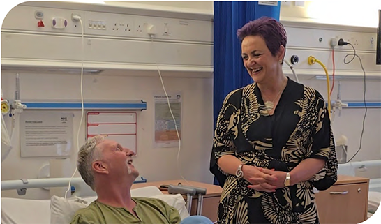 Cabinet Secretary Angela Constance chats to a patient in a hospital bed 