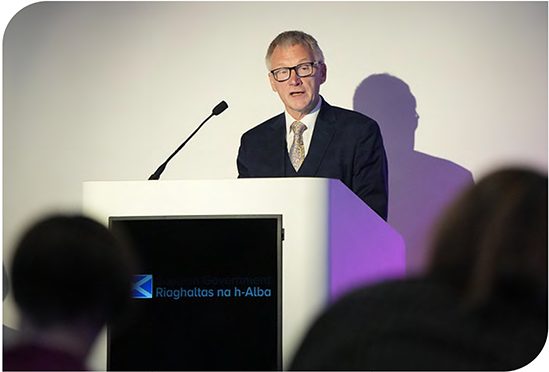 Cabinet Secretary Ivan McKee gives a speech at a lectern 
