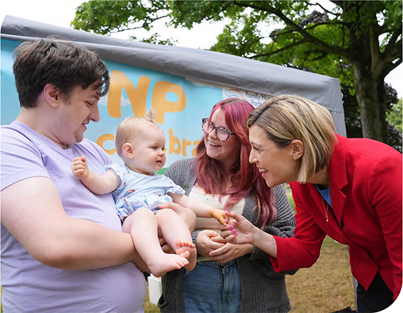 Deputy First Minister with a family and a baby at a Whole Family Support event 