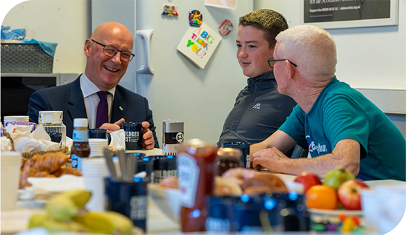 First Minister John Swinney joins a conversation round a breakfast table 