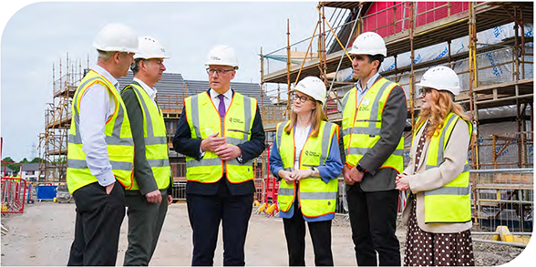 First Minister talks to a group of people at a housing construction site 